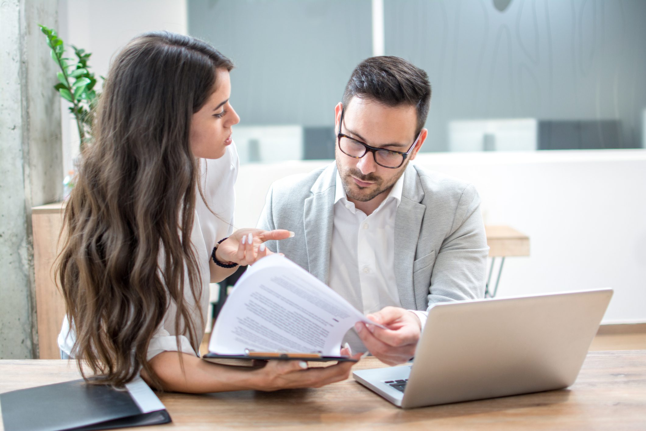 Two professionals discussing documents in an office setting.