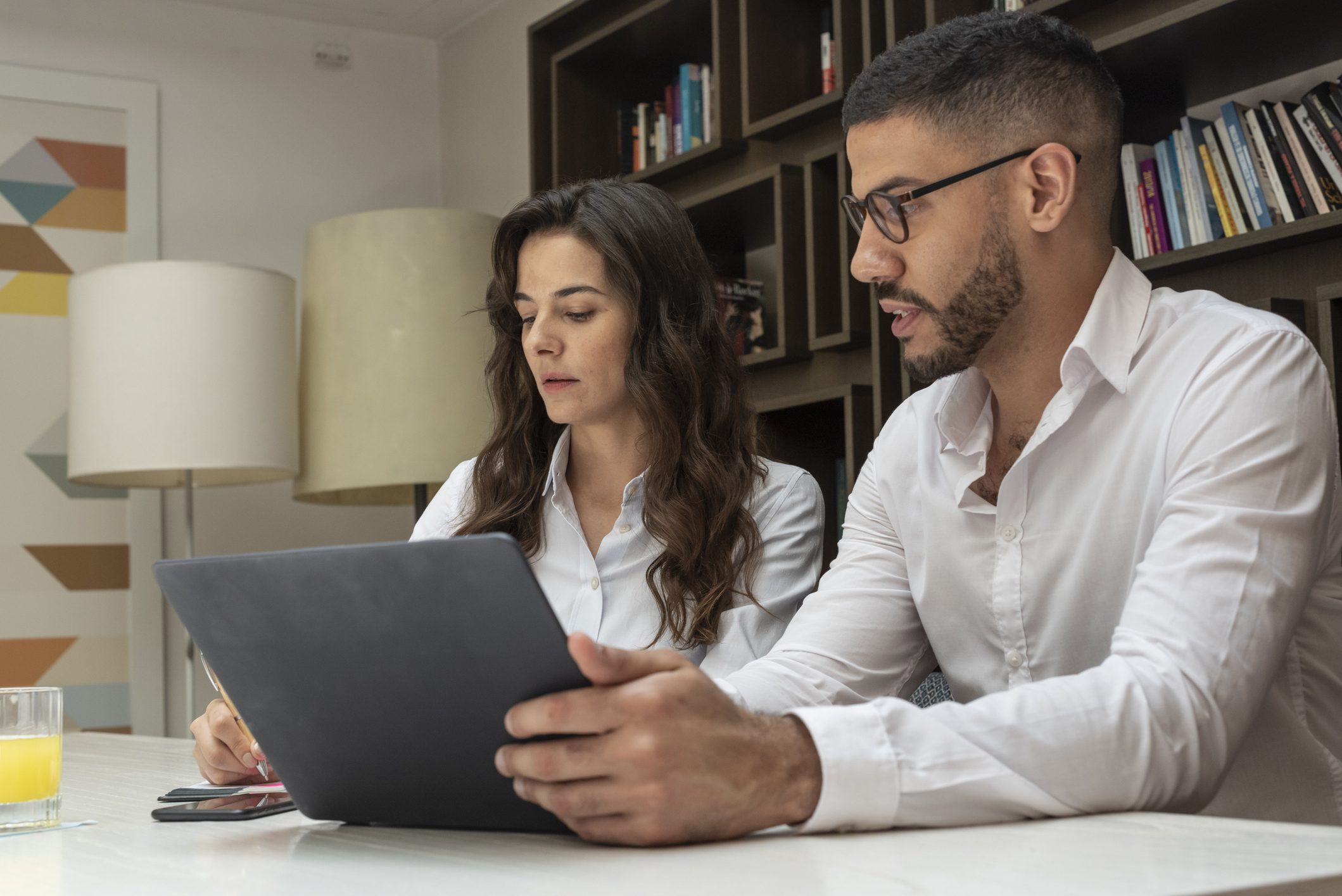 Two professionals collaborating over a tablet in an office.