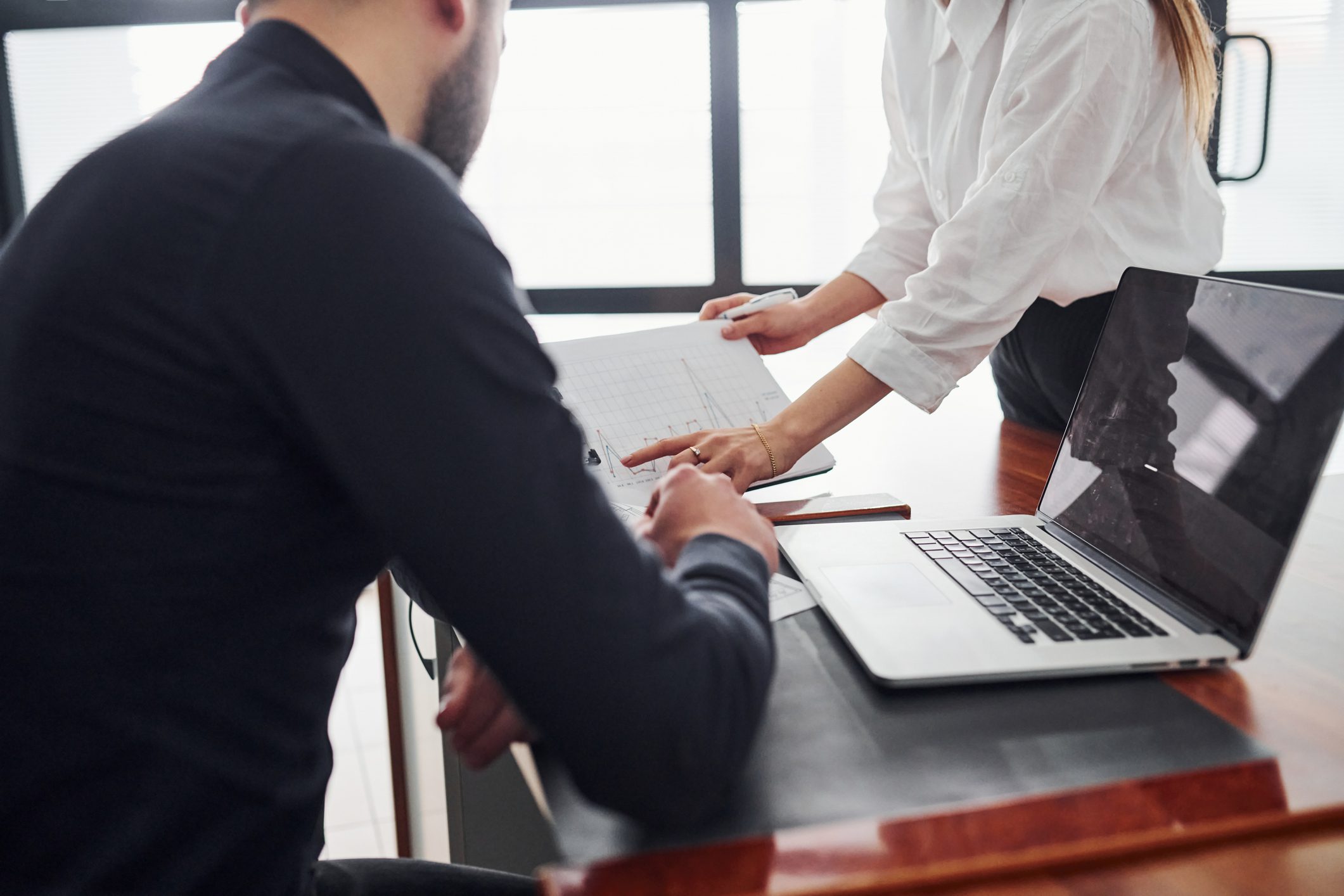 Business meeting discussion with documents and laptop.