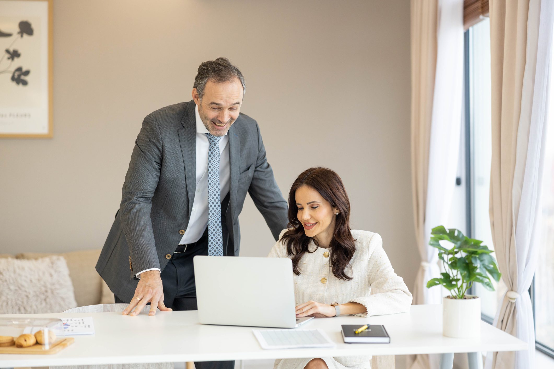 A man and woman collaborating at a laptop in a bright office.