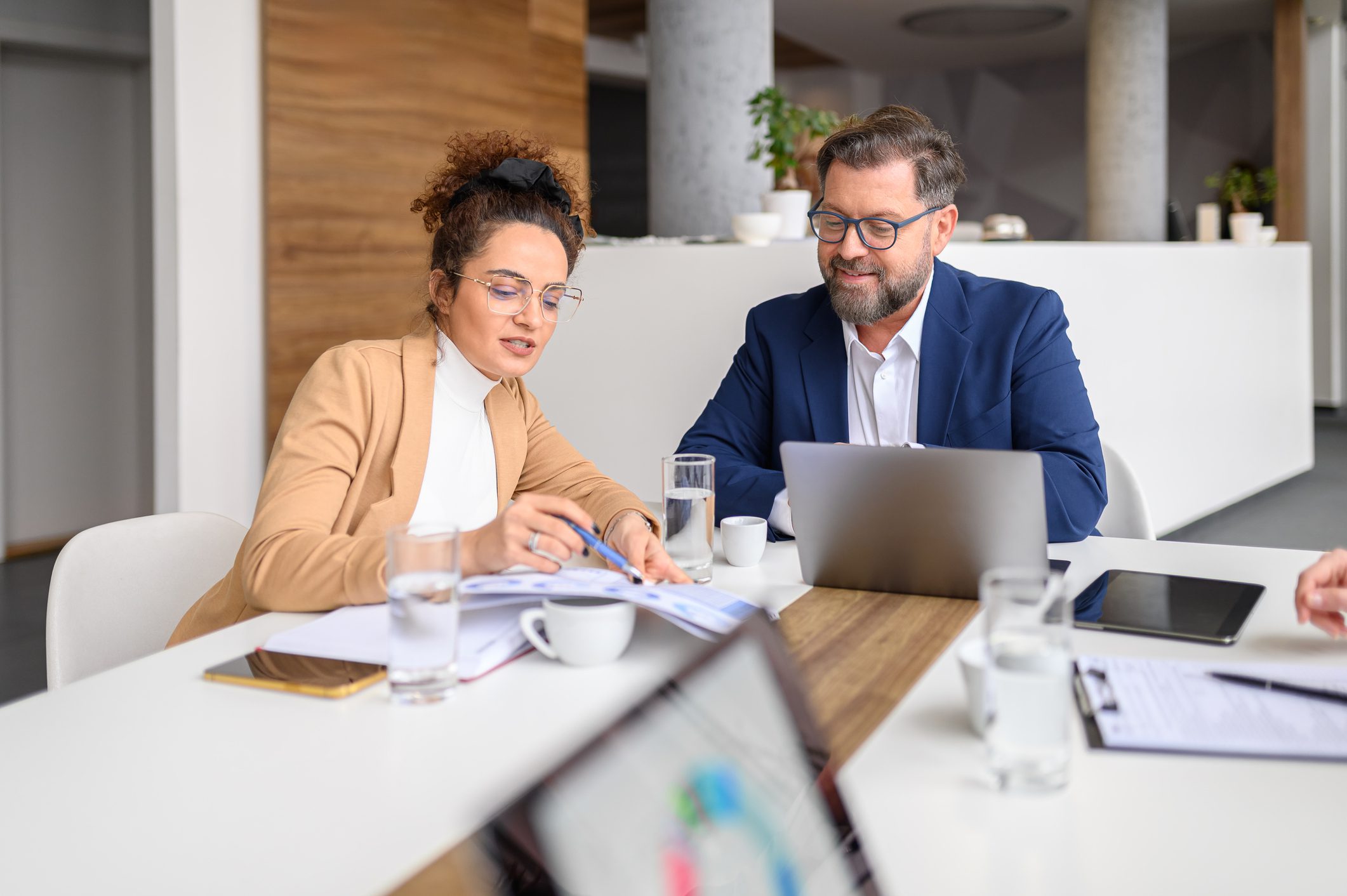 Two professionals discussing documents in a modern office setting.
